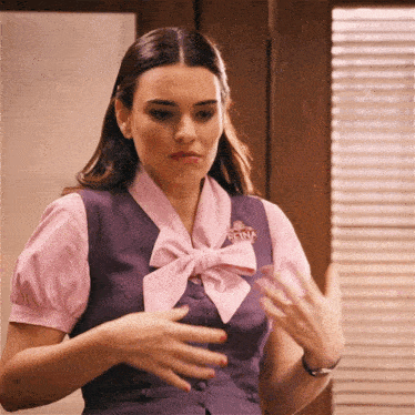 a woman wearing a purple vest with a pink bow and a badge that says reina