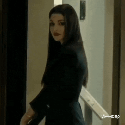 a woman with long hair is standing in front of a door .