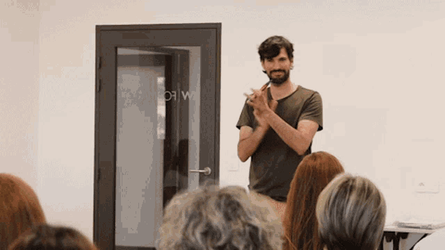 a man stands in front of a group of people in front of a door that says ' a canton w ' on it