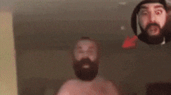 a shirtless man with a beard is talking to another man .