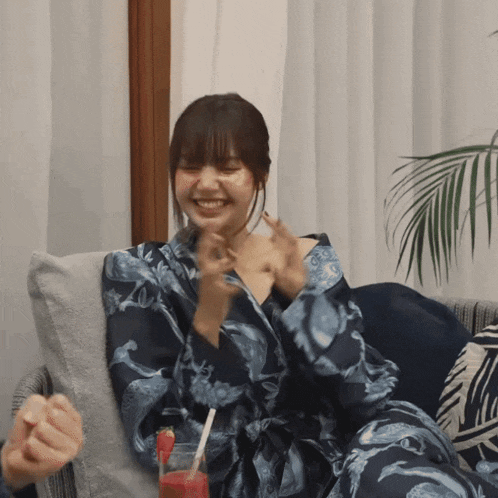 a woman in a blue robe is sitting on a couch with a drink in front of her