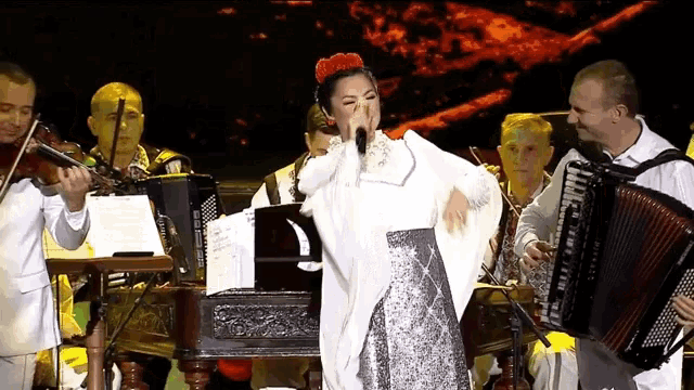 a woman singing into a microphone in front of an accordion