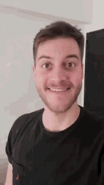 a man with a beard and a black shirt is smiling .