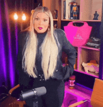 a woman with blonde hair is standing in front of a microphone in a room .