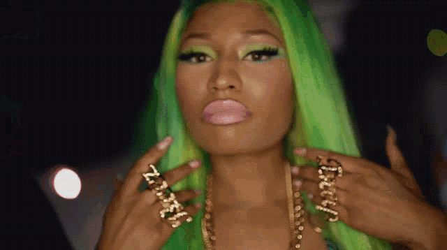 a woman with green hair is wearing a gold chain and a ring that says nicki