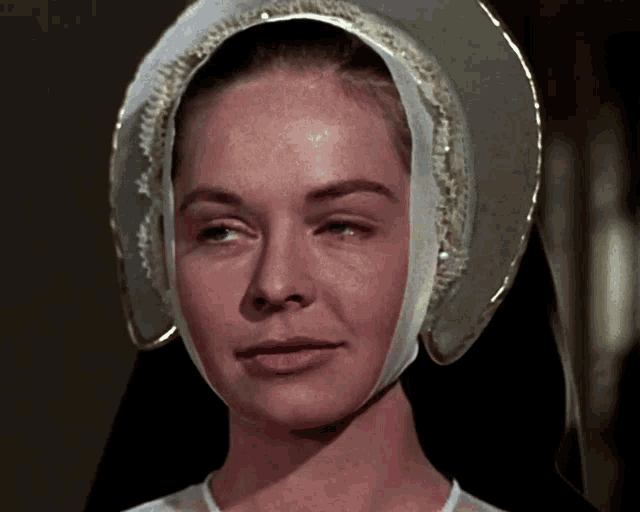 a close up of a woman wearing a white and gold hat