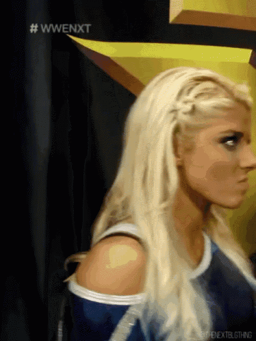 a woman with blonde hair is standing in front of a sign that says wwenext