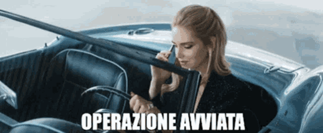 a woman is sitting in a car talking on a cell phone and the words operazione avviata are visible