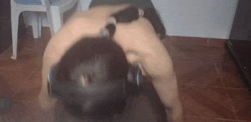 a man is doing push ups with a dumbbell on his head