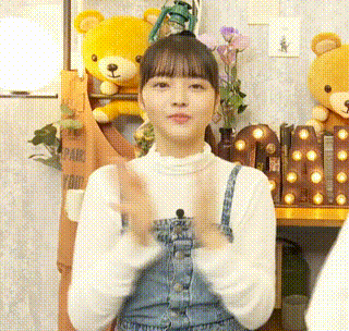 a woman in overalls is sitting in front of a teddy bear .