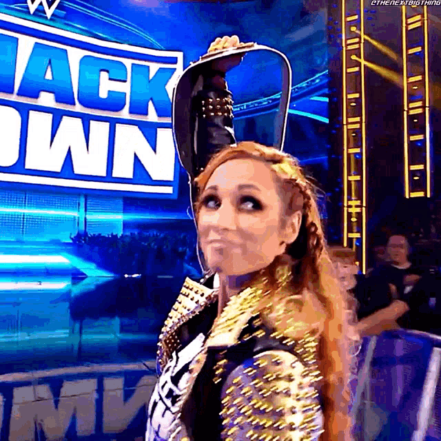 a woman is holding a belt in front of a sign that says ' back down '