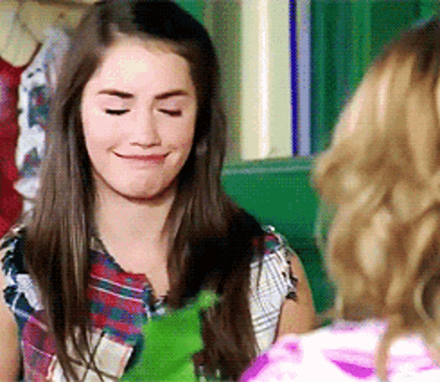 a girl in a plaid shirt is smiling and looking down