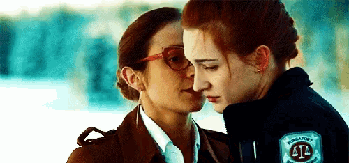 a couple of women are hugging each other and one of them is wearing glasses .