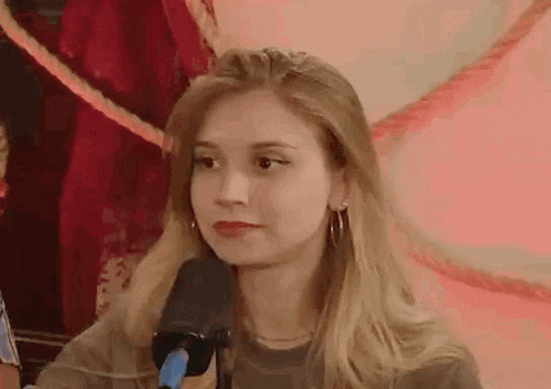 a woman is sitting in front of a microphone and making a funny face .