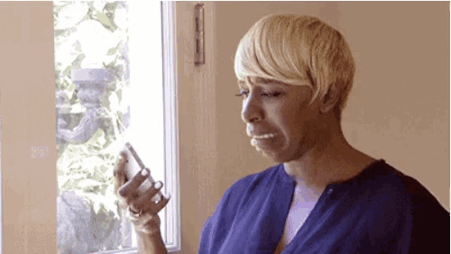 a woman is crying while looking at her phone .