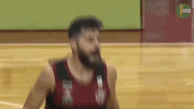 a man with a beard is playing basketball on a court with the nba logo in the background