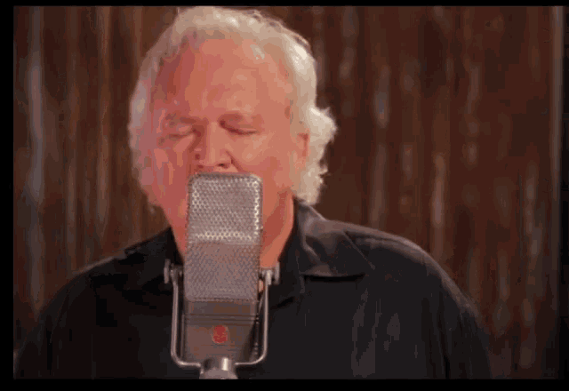 a man singing into a microphone with a red emblem on it