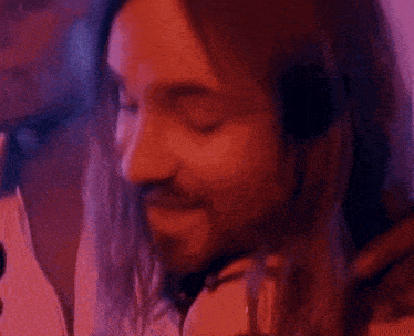 two men are sitting next to each other in a room with purple lights behind them