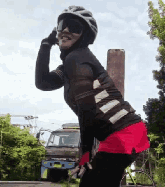 a woman wearing a helmet and sunglasses is talking on a cell phone