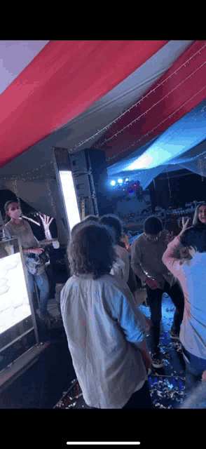 a group of people are dancing in a room with a man playing a guitar in the background