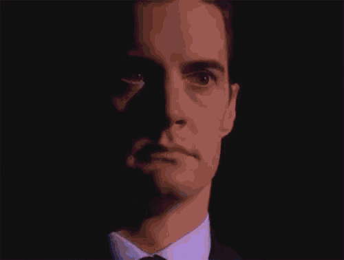a man in a suit and tie is making a funny face with his eyes closed .
