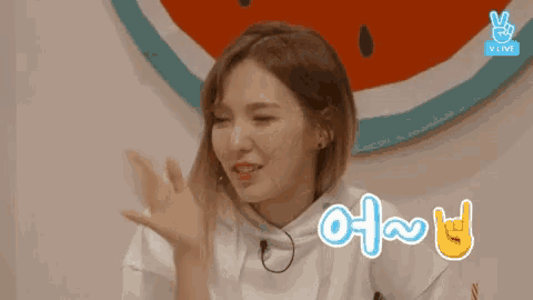 a girl making a peace sign in front of a watermelon sign