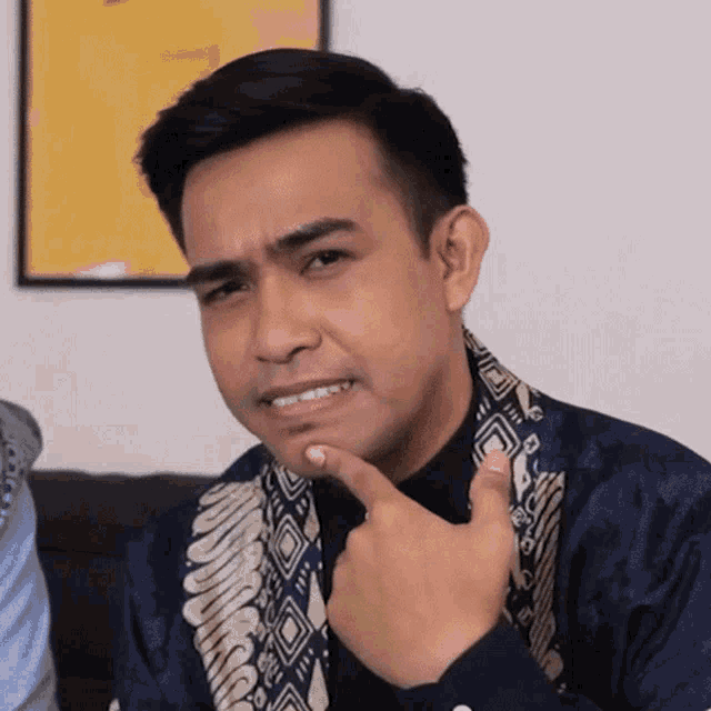 a man wearing a blue shirt and a scarf is making a funny face