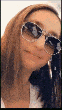 a woman wearing sunglasses and earrings is making a face .
