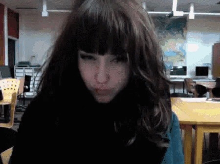 a girl with long dark hair is making a funny face in front of a map of the world