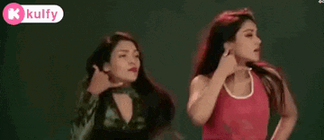 two women are standing next to each other in front of a green background . one of the women is wearing a red tank top .
