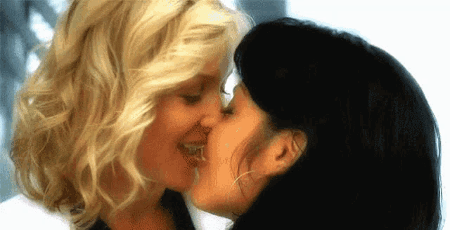 a couple of women are kissing each other on the cheek .