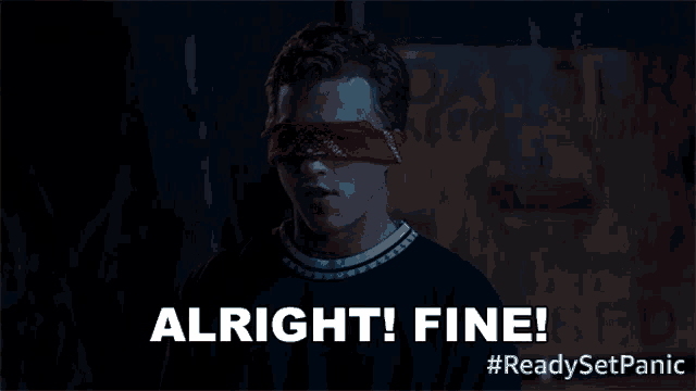 a man with his eyes blindfolded says " alright fine " in front of a danger sign