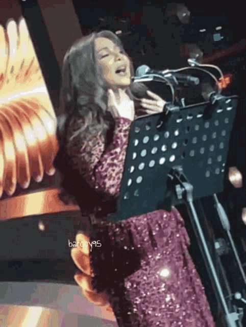 a woman in a purple dress singing into a microphone with baron95 written on the bottom of the image