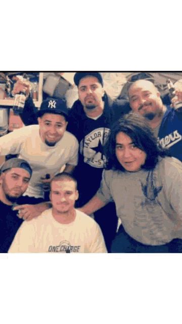 a group of men are posing for a picture and one of them has a ny hat on