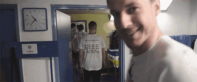 a man wearing a shirt that says buzzard stands in a room