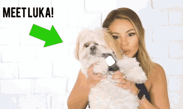 a woman holding a small white dog with the words meet luka behind her