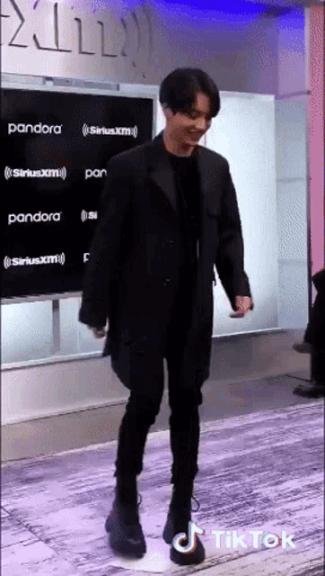 a man in a black coat is walking in front of a sign that says siriusxm