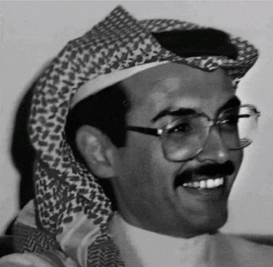 a man wearing glasses and a head scarf is smiling