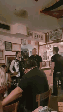 a man is playing an accordion while another man stands behind him
