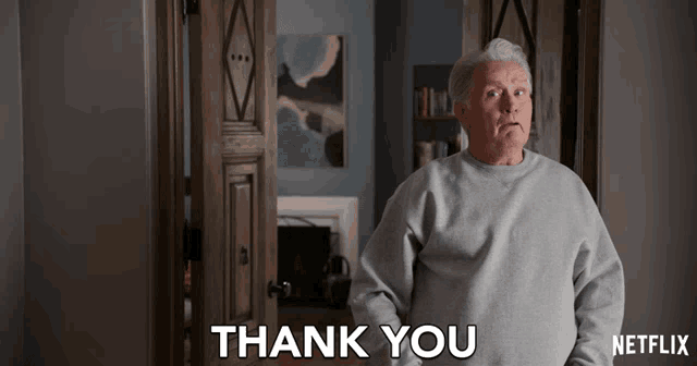 a man in a grey sweater says thank you in front of a netflix logo