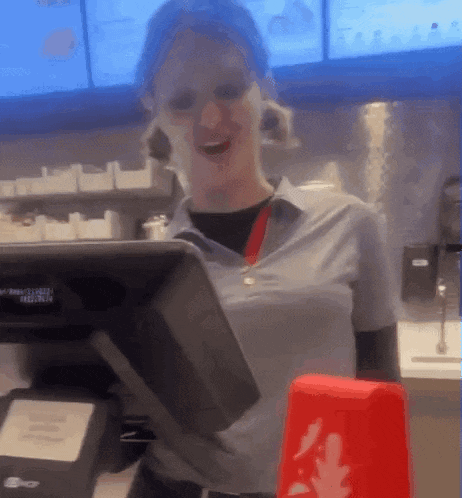 a woman in a blue shirt is smiling while looking at a monitor