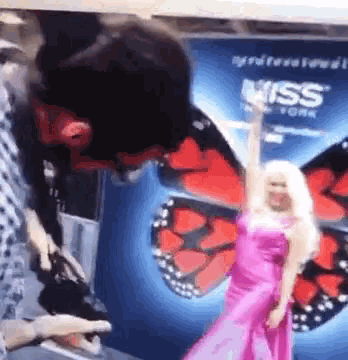 a woman in a pink dress is standing in front of a pepsi advertisement