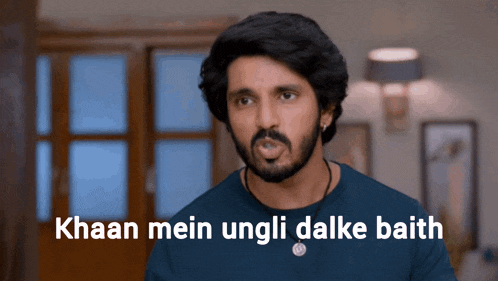 a man with a beard is wearing a blue shirt with the words " haan mein ungli dalke baith " on the bottom