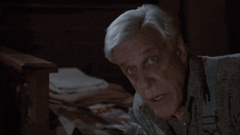 a man with gray hair is laying on a bed looking at something