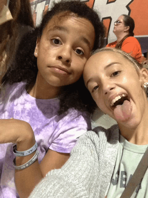 two girls are posing for a picture and one has a bracelet on her arm that says ' i love you '