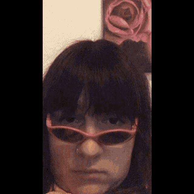 a woman wearing pink sunglasses and a nose ring