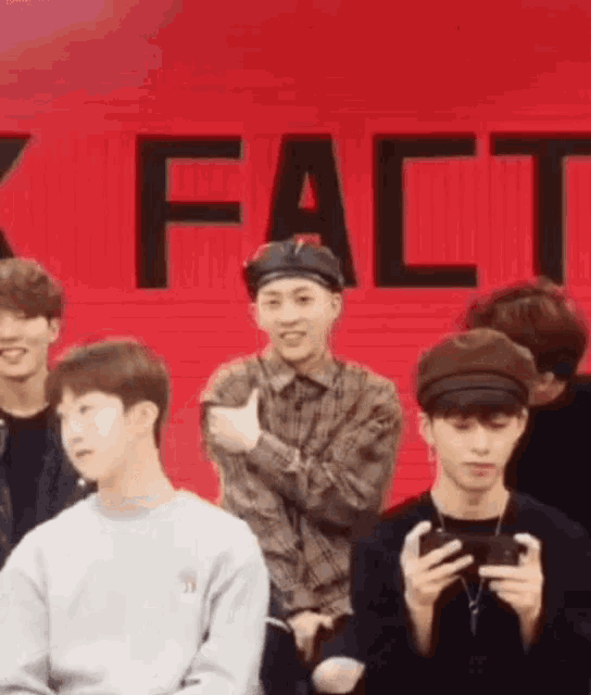 a group of young men are sitting in front of a wall that says fact