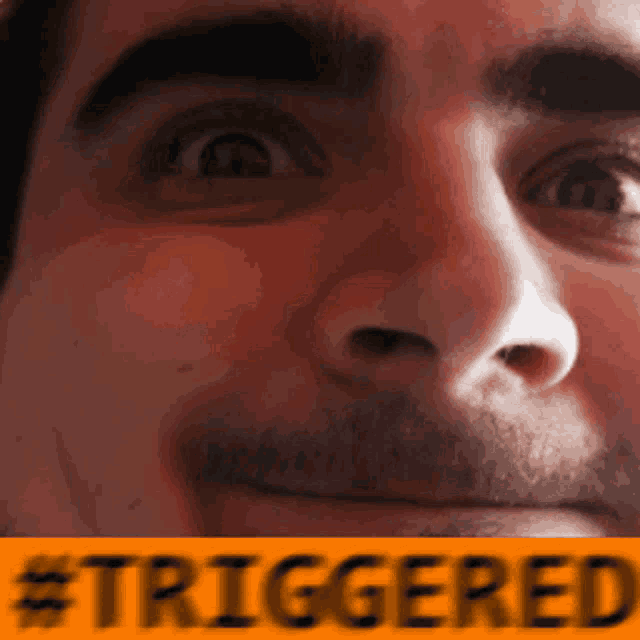 a close up of a man 's face with the words #triggered in the corner