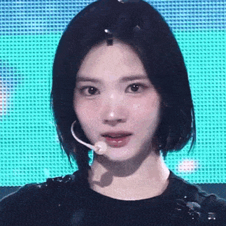 a close up of a woman wearing a microphone and a black shirt .