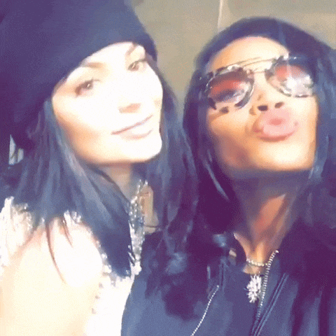 two women wearing sunglasses and a beanie pose for a photo